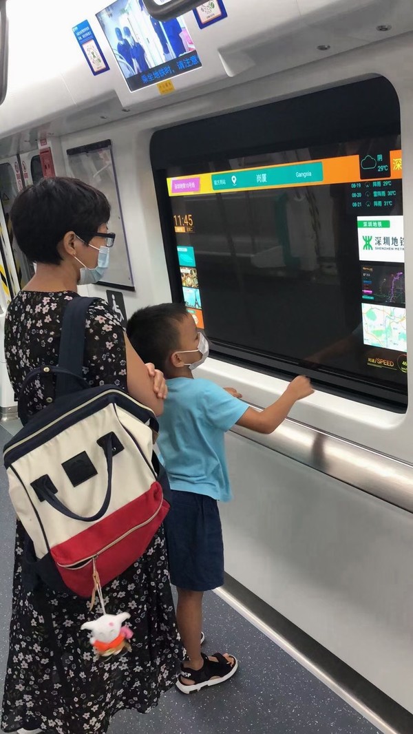 중국 심천 지하철에 설치된 LG디스플레이 55인치 투명 OLED를 승객들이 살펴보고 있다. 사진. LG디스플레이 제공