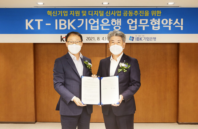 윤종원 IBK업은행장(오른쪽)과 구현모 KT대표이사가 협약식을 마친 후 협약서를 들어보이고 있다. 사진. 기업은행.