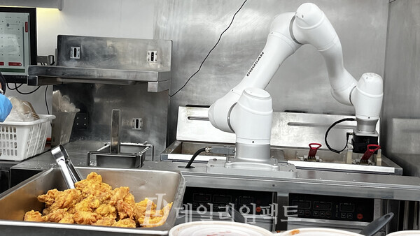 두산로보틱스의 협동로봇이 튀김기에 들어간 치킨에 스냅을 주며 치킨이 고루 익도록 만들고 있는 모습. 사진=김현일 기자