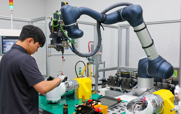 두산로보틱스 수원공장 내 자동화셀에서 작업자와 협동로봇이 함께 로봇을 만들고 있는 모습. 작업자가 너트를 살짝 돌려놓으면 로봇이 이를 완전히 체결하는 식으로 작업이 이뤄진다. 사진=두산로보틱스