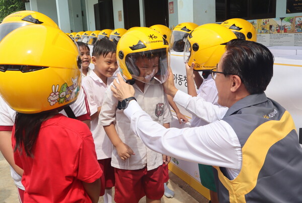 지난 16일 안전모 전달식에 참여한 KB손해보험 조정래 인니법인장이 Sinar Cahaya Kasih 학교 학생들에게 안전모를 씌워주고 있다/사진=KB손해보험 제공