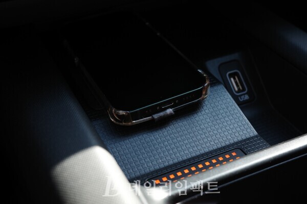 아이오닉 6의 무선충전 패드에서 스마트폰이 충전중인 모습. 하단의 램프가 주황색으로 점등하며 충전중임을 나타낸다. /사진=김현일 기자